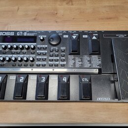 Černý kytarový efektový procesor s nápisem BOSS GT-8 GUITAR EFFECTS PROCESSOR. Zařízení má ovládací panel s knoflíky, tlačítky a displejem, v dolní č…