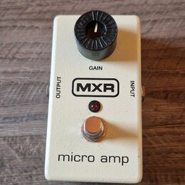 Bílý kytarový efekt pedál s černým knoflíkem. Na šasi jsou viditelné nápisy GAIN, OUTPUT, INPUT a logo MXR v obdélníku. Ve spodní části je uveden náz…