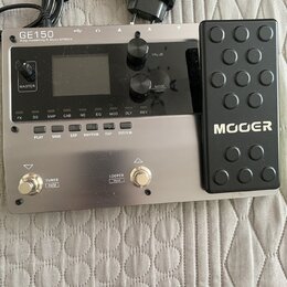 Stříbrný kytarový procesor s černým expresním pedálem, na kterém je bílý nápis MOER. Na horní části přístroje je text GE150 Amp modelling & Multi Eff…