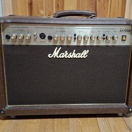 Kombinovaný kytarový zesilovač v hnědém vinylovém potahu s černou přední mřížkou. Na čelním panelu je nápis Marshall a označení modelu AS50R Acoustic…