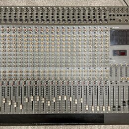 Široký míchací pult s šedým povrchem a černým rámem. Na pravé straně je červené logo TASCAM a vedle něj vertikální nápis M-2524. Přístroj obsahuje ve…