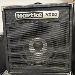Černý basový kombo zesilovač s kovovou ochrannou hranou. V horní části je stříbrný nápis Hartke HD 50 a pod ním černá kovová mřížka reproduktoru. Zes…