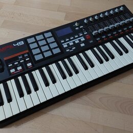 Černý MIDI kontrolér s klaviaturní součástí a bílými a černými klávesami. Na levé straně je nápis AKAI professional MPK49 a mřížka šedých padů. Horní…