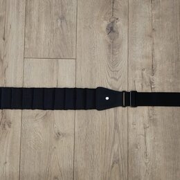Černý popruh na hudební nástroj s texturovaným, vlnovitým povrchem v hlavní části. Na pravé straně je bílý nápis mono. Popruh má na koncích otvory pr…