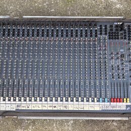 Široký míchací pult v šedé barvě umístěný v transportním kufru. V pravém horním rohu je viditelné logo s nápisem Soundcraft. Spodní hranu pultu doplň…