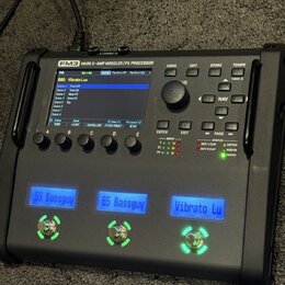 Černý kytarový procesor s nápisem FM3 MARK II - AMP MODELER/FX PROCESSOR. Zařízení má displej, ovládací knoflík a tři podsvícená tlačítka s nápisy 59…