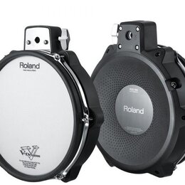 Dvě elektronické bubnové pady značky Roland. Levý pad má bílou membránu s nápisy „Roland“, „Head made by REMO“ a „V-Drums“. Pravý pad je z černého pl…