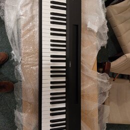 Černý digitální klavír s bílými a černými klávesami. Na pravé straně korpusu je viditelný nápis YAMAHA. Nástroj leží na dřevěném povrchu a je částečn…