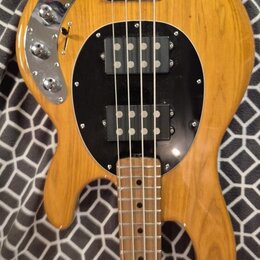 Kytara s přírodním dřevěným povrchem a černým kruhovým pickguardem. Na těle jsou dva černé humbuckery, chromovaný most a ovládací panel s dvěma knofl…