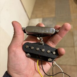 Fotografie zachycuje dva elektrické kytarové snímače držené v dlani. Horní snímač je typu humbucker s chromovaným krytem, spodní je jednoduchý snímač…