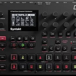 Černý digitální sekvencer a syntetizátor s nápisem Syntakt. Zařízení má displej, na kterém je vidět text 12 Track Drum Computer & Synthesizer a název…