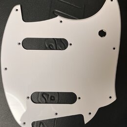 Bílá plastová pickguard pro elektrickou kytaru s dvěma obdélníkovými výřezy na snímače a kulatým otvorem pro ovládací prvek. Povrch je hladký, bez vi…