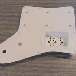 Bílá pickguard pro elektrickou kytaru s vyfrézovaným otvorem pro snímač. Povrch je hladký a čistý, bez viditelných značek, log nebo nápisů. V materiá…