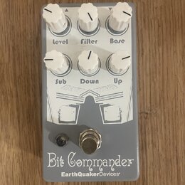 Šedý kytarový efekt s bílými ovládacími knoflíky. Na spodní části je nápis Bit Commander a pod ním značka EarthQuakerDevices. Knoflíky jsou popsány j…