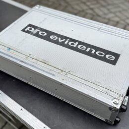 Stříbrný transportní kufr z hliníku s texturovaným povrchem. Uprostřed je černý nápis pro evidence. Povrch vykazuje známky opotřebení v podobě škrába…