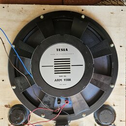 Na dřevěné desce je umístěn velký černý reproduktor s magnetem. Na středovém bílém štítku je nápis TESLA, MADE IN CZECHOSLOVAKIA, 50 W-8Ω a ARM 9308,…
