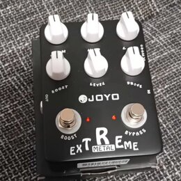 Černý kytarový efekt s bílými ovládacími knoflíky. Na šasi je uveden nápis JOYO EXTREME METAL a označení ovládacích prvků DRIVE, LEVEL a BOOST. Jsou…