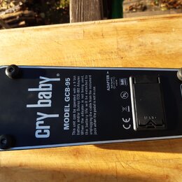Spodní strana černého efekt pedálu s nápisem cry baby. a označením MODEL GCB-95. Na povrchu je vidět logo Dunlop, informace o napájení ADAPTER 9 Volt…