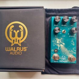 Na fotografii je tyrkysový kytarový efekt v černém textilním vakle a vedle něj černá krabice s goldeným logem a nápisem WALRUS AUDIO. Na efektu jsou…