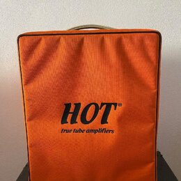 Oranžový textilní kryt na hudební zesilovač. Uprostřed je černý nápis HOT® a pod ním menší text true tube amplifiers. Kryt vykazuje mírné opotřebení…