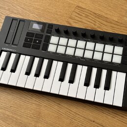 Černý MIDI kontrolér s klaviaturní klávesou a mřížkou bílých podsvícených polí. Na levé straně je nápis LAUNCHKEY a ovládací prvky pro Pitch a Modula…