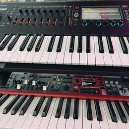 Dvě klávesové nástroje umístěné na stojanu nad sebou. Horní černý instrument nese v levém horním rohu logo Roland a vedle něj neúplný nápis ROM. Spod…