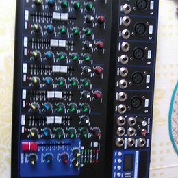 Černý mixážní pult s modrým rámem. Na pravé straně jsou vstupní konektory XLR a jack, v dolní části je digitální displej. Ovládací panel obsahuje pos…