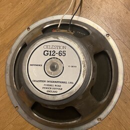 Kruhový reproduktor s kovovým rámem a magnetem. Na bílém štítku je uveden nápis CELESTION G12-65, IMPEDANCE 15 OHMS a adresa CELESTION INTERNATIONAL…