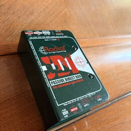 Tmavě zelená pasivní DI box s nápisem Radial engineering a modelem JDI. Na horní straně je text PASSIVE DIRECT BOX, TRNSFORMER ISOLATED DI a Made in…