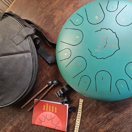 Zelený steel tongue drum s vyrytými čísly 1 až 10 a centrálním logem LENA v ornamentálním kruhu. K nástroji patří černý přepravní vak, dva dřevěné pa…