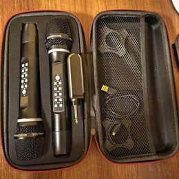 Černý přepravní kufr s červeným zipem obsahuje dva bezdrátové mikrofony a jeden přijímač. Na hlavách mikrofonů je nápis MICROPHONE a WIRELESS MICROPH…