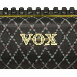 Černý kytarový kombo zesilovač s látkovou mřížkou v kosočtvercovém vzoru. Uprostřed je umístěno zlaté logo VOX. Horní ovládací panel obsahuje řadu če…