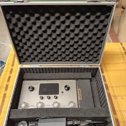 Stříbrný kytarový procesor s nápisem AMPERO a podtitulem Guitar Processor v černé tlumící pěnové kufře. Na pravém boku zařízení je oranžový nápis HOT…