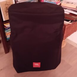 Černý textilní kryt na reproduktor nebo subwoofer. V dolní části je umístěno červené obdélníkové logo s bílým nápisem JBL. Povrch látky je v dobrém s…