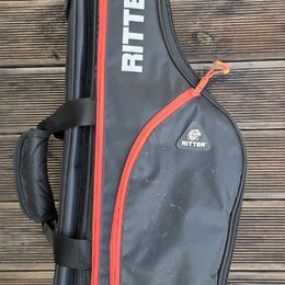 Černý polstrovatý pouzdro na hudební nástroj s červeným zipem. Na přední straně je bílý nápis RITTER™ a menší logo s textem RITTER. Povrch materiálu…