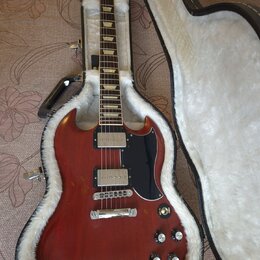 Elektrická kytara s červeným trupem a černým pickguardem v otevřeném hnědém kufru s bílou vnitřní výplní. Na hlavě kytary je viditelné logo Epiphone.…
