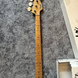 Hrabedlo basové kytary s přírodním dřevěným povrchem a hmatníkem z jasného dřeva. Na hlavě je viditelné logo Fender a nápis Jazz Bass. Nástroj vykazu…