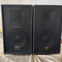 Dvě černé reproduktorové bedny s kovovými mřížkami. Na spodní části obou beden je umístěn nápis RH SOUND. Povrch beden vykazuje mírné opotřebení hran.