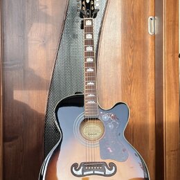 Akustická kytara s vyřezem (cutaway) v provedení sunburst. Na hlavě je nápis Epiphone a na hradle se nachází štítek s textem GUARANTEED Lifetime Warr…