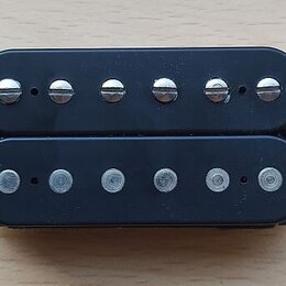 Černý humbucker s dvěma řadami šesti snímačů. Horní řada má viditelné šroubovací hlavy, spodní řada jsou hladké čepy. Na komponentu nejsou viditelné…