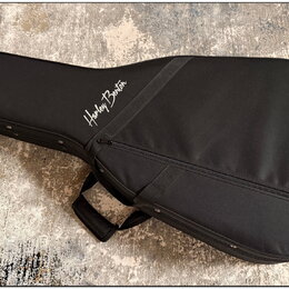 Černý polstrovatý pouzdro (gig bag) na kytaru s rukojetí. Na přední straně je bílý nápis Harley Benton. Povrch materiálu vypadá čistě a v dobrém stav…