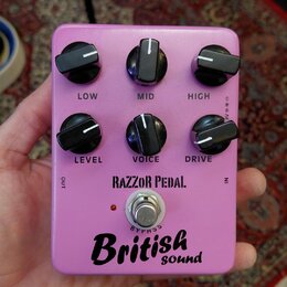 Růžový kytarový efekt s šesti černými ovládacími knoflíky. Na pedálu jsou nápisy LOW, MID, HIGH, LEVEL, VOICE a DRIVE, značka RAZZOR PEDAL. Ve spodní…