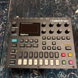 Digitální syntetizátor Elektron Digitone v šedé barvě. Na horní části je nápis Polyphonic Digital Synthesizer a logo Elektron. Zařízení obsahuje disp…