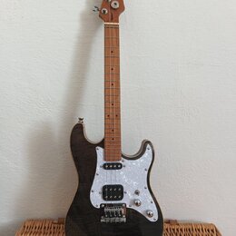 Elektrická kytara s tmavým, pravděpodobně černým lakem s viditelnou strukturou dřeva. Má bílý perleťový pickguard, jeden humbucker u mostu a dva sním…