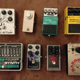 Fotografie zobrazuje osm kytarových efektů rozložených ve dvou řadách. V horní řadě jsou pedály s nápisy BASS AUTOWAH, DFZ, Boss Bass Comp BC-1X a Bo…