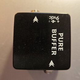 Černý kytarový pedál s hranatým tvarem. Na povrchu je bílý nápis PURE BUFFER a označení napájení + - 9vdc. Vedle textu jsou dvě bílé šipky směřující…