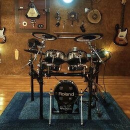Elektronická bicí souprava značky Roland, model V-Drums. Sestava obsahuje několik padů v kovovém provedení a dva činely na stojanu. Celý komplet je u…