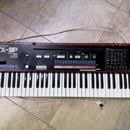 Černý syntetizátor s červeným horním panelem. Na levé straně je bílý nápis Roland a model JX-3P, pod kterým je text PROGRAMMABLE PRESET POLYPHONIC SY…