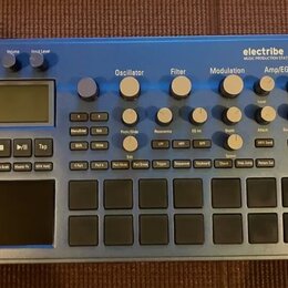 Modrý sekvenční syntetizátor s nápisy electribe MUSIC PRODUCTION STATION a KORG. Zařízení obsahuje displej, několik otočných knoflíků rozdělených do…