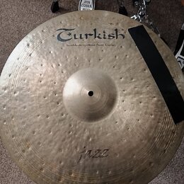 Kulatý mosazný činel s kovaným povrchem. Na horní části je černý nápis Turkish a pod ním text handmade cymbals from Turkey. Ve spodní části je rukopi…